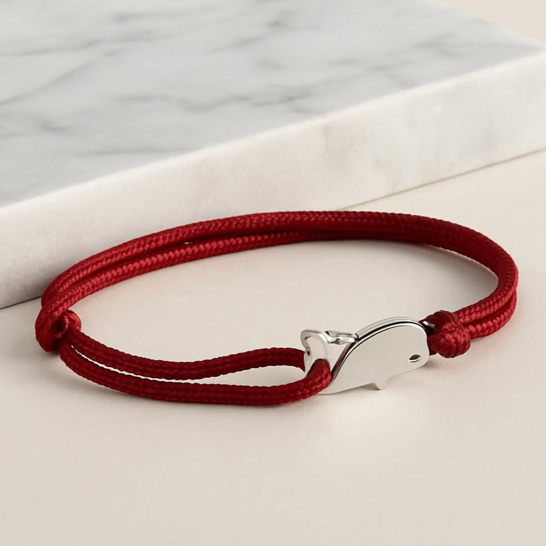 Red braided bracelet with a silver clasp on a light background