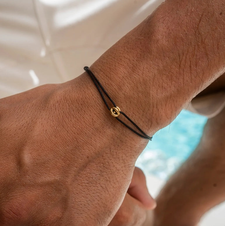 A stylish black bracelet with a golden lucky symbol, elegantly worn on the wrist, adding a touch of sophistication and meaning to any outfit.