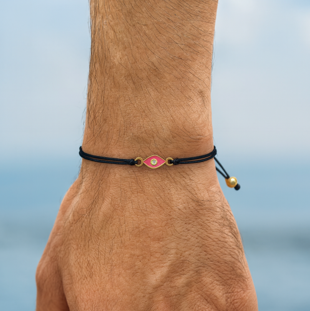Bracelet with a pink and gold clasp on a wrist against a blurred background