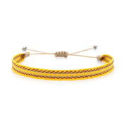 Bright yellow handmade woven bracelet with red and beige pattern, laid out on a white background with adjustable beige cord.