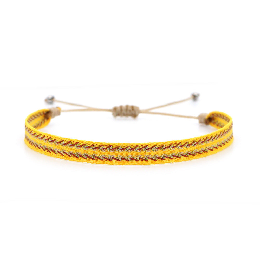 Bright yellow handmade woven bracelet with red and beige pattern, laid out on a white background with adjustable beige cord.