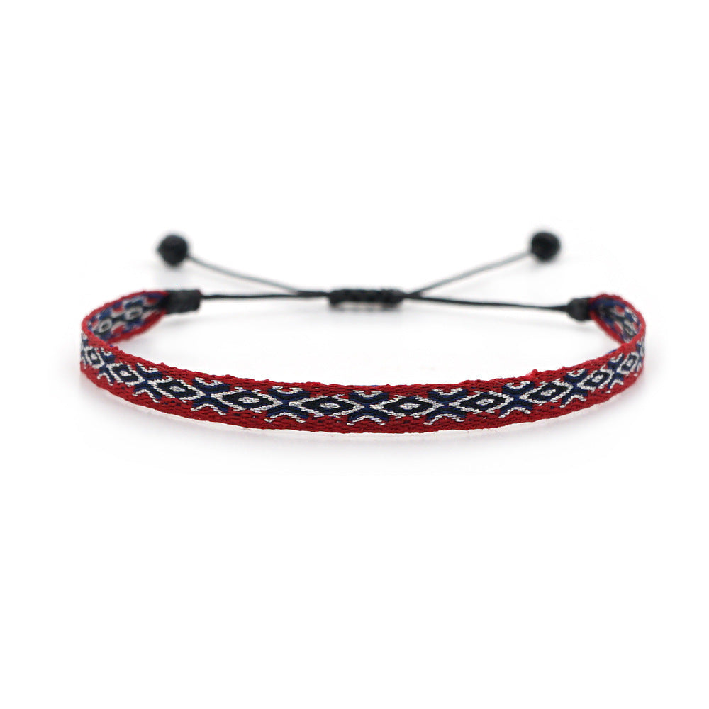 Burgundy woven bracelet with navy and white geometric pattern, featuring adjustable black cord.
