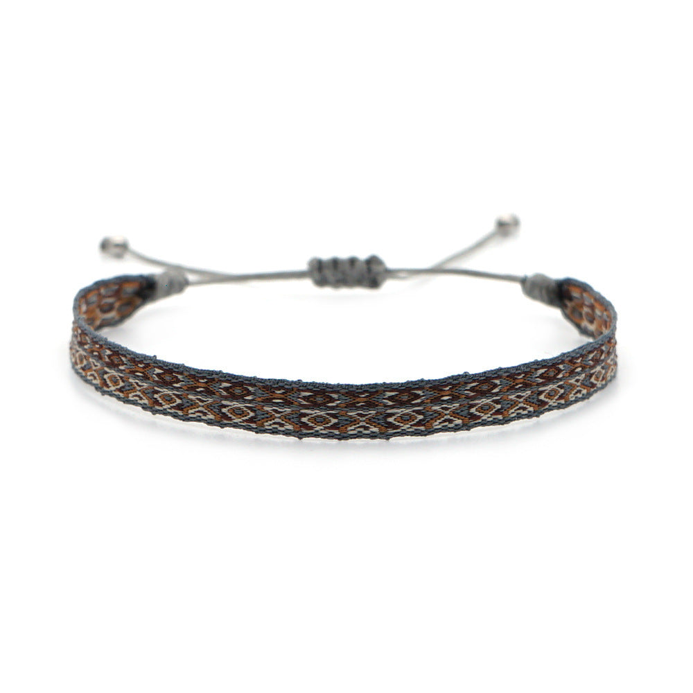 Handwoven bracelet with brown, ivory, and grey thread pattern, displayed on a white background with adjustable grey cord.