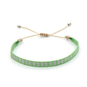 Bright green handmade bracelet with white woven diamond pattern and beige adjustable cord.