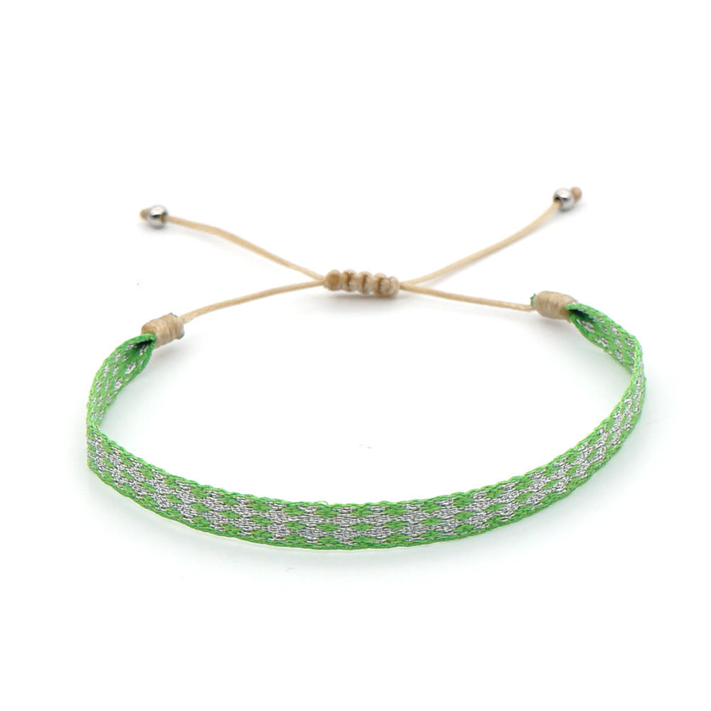 Bright green handmade bracelet with white woven diamond pattern and beige adjustable cord.