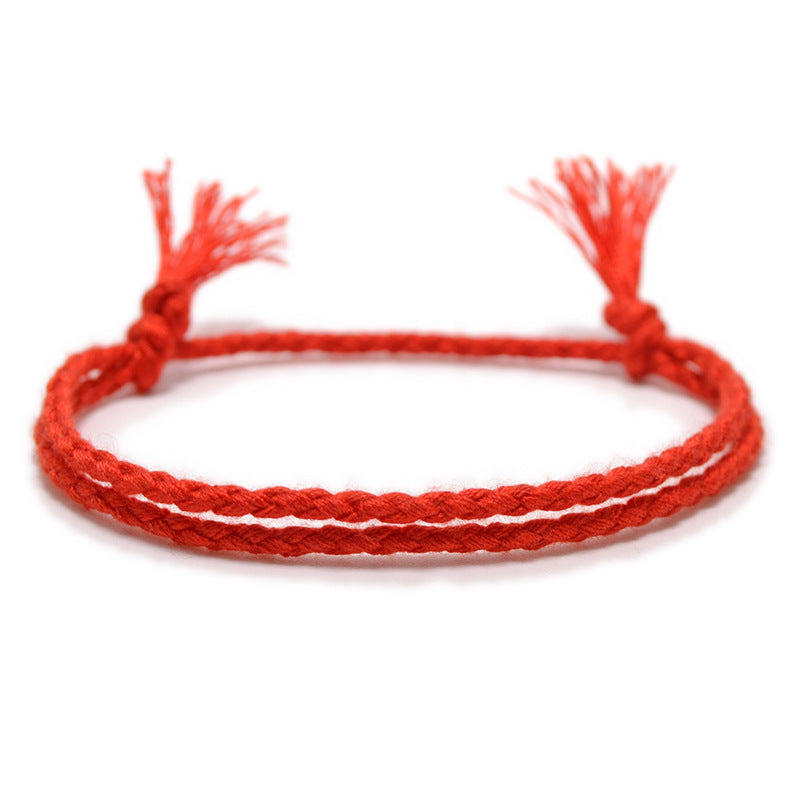 A sunset red braided bracelet with a handwoven design and adjustable knotted closure, showcasing fine European craftsmanship.