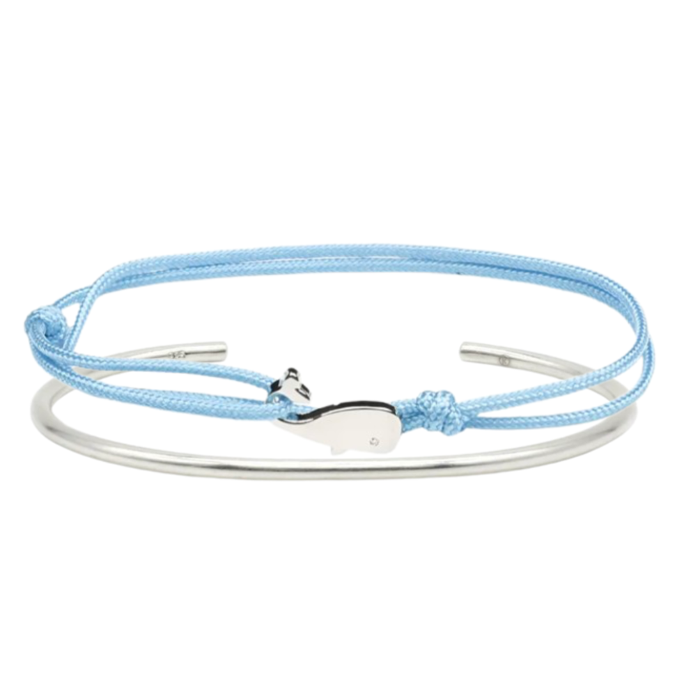 Silver bangle with light blue cord bracelet featuring a silver dolphin charm – minimalist nautical-inspired design.