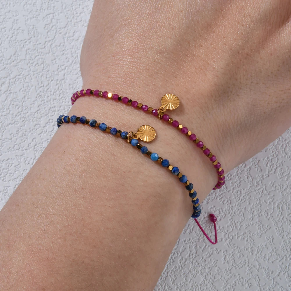 Blue and gold beaded bracelet with round gold charm on arm