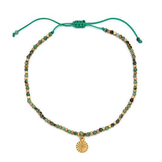 Green and gold bracelet with a circular gold charm