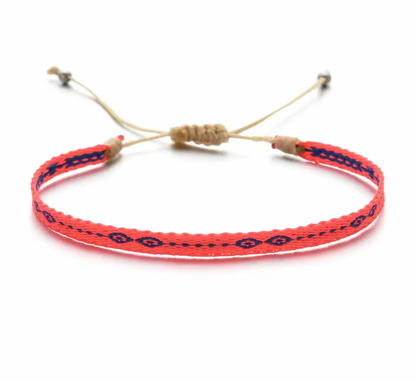 Coral red handmade bracelet with navy blue diamond pattern and beige adjustable cord.