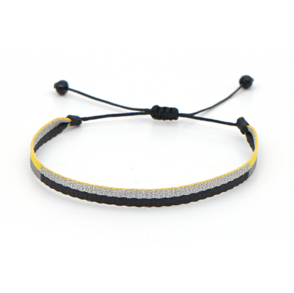 Minimal braided bracelet with black, silver, and yellow stripes, featuring adjustable black drawstring ends