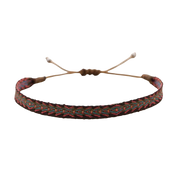 Handmade woven bracelet in red, green, and black with tribal-inspired pattern, displayed on a soft beige pedestal.