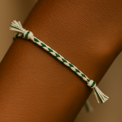 Green and white braided bracelet on a wrist against a neutral background