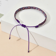Purple braided necklace with beads on a white and beige background