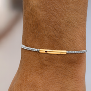 Bracelet with gold and silver clasp on a wrist against a neutral background
