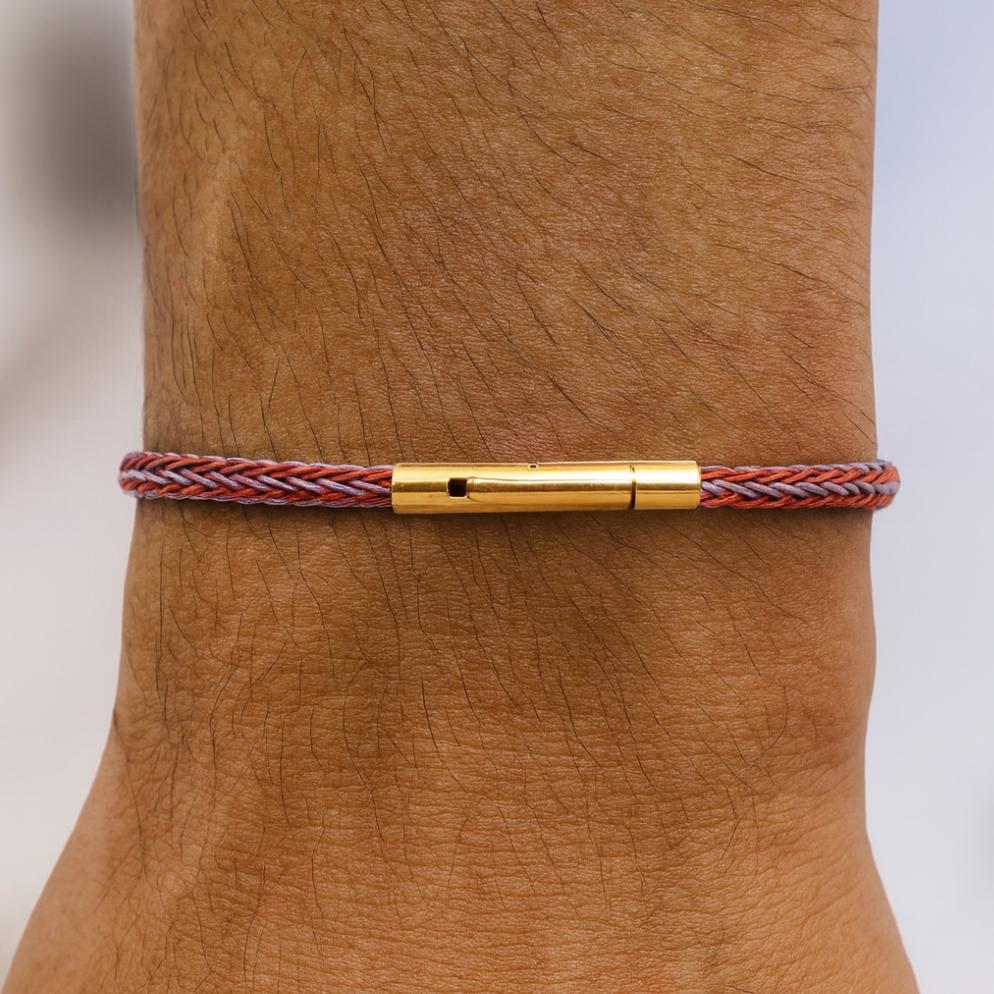 Bracelet with gold clasp on a wrist against a neutral background