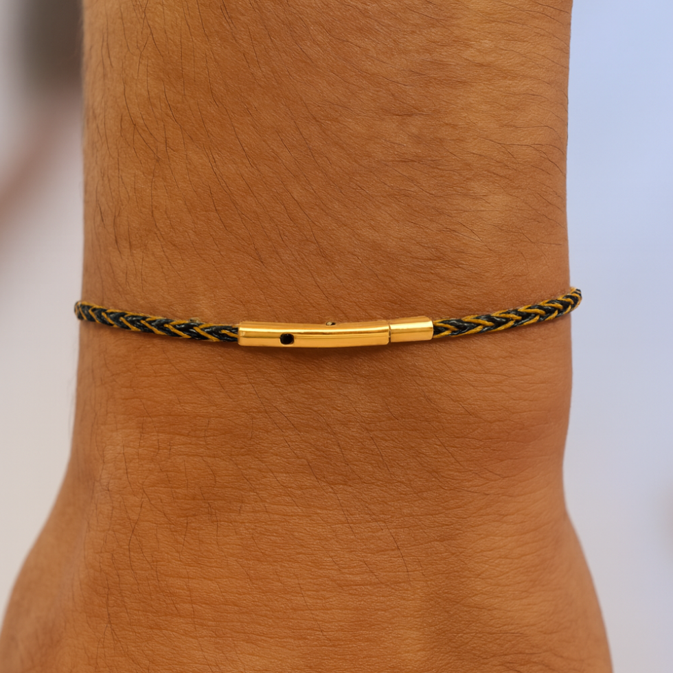 Gold and black braided anklet on a person's ankle with a blurred background