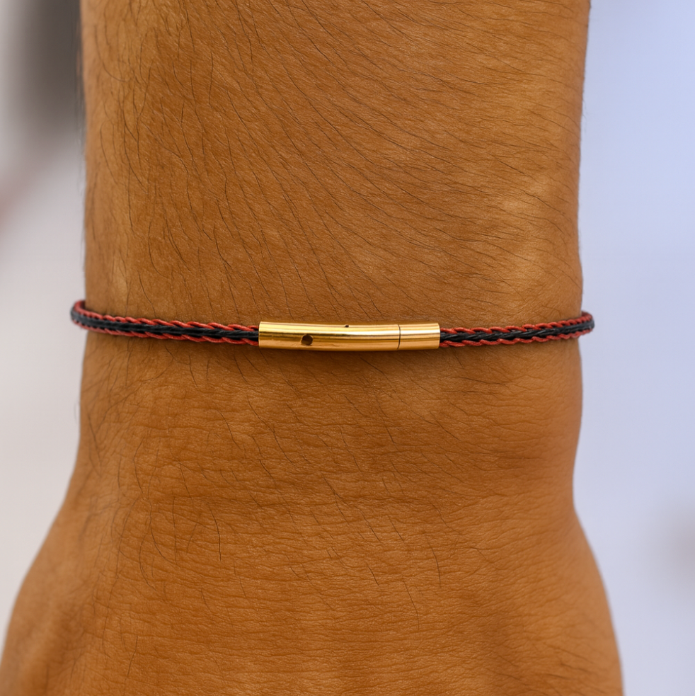 Bracelet with gold clasp on a wrist against a neutral background