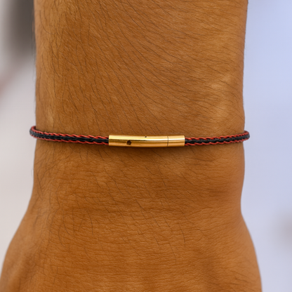 Bracelet with gold clasp on a wrist against a neutral background