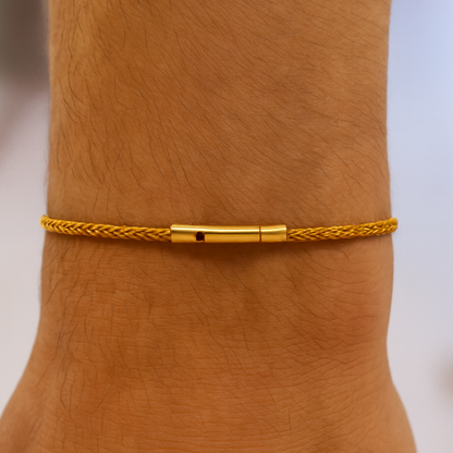 Gold braided bracelet on a wrist with a blurred background