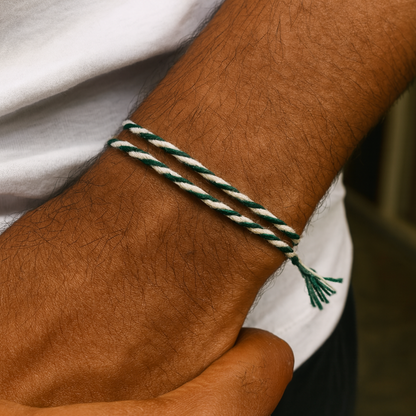 Close-up of a wrist with a green and white braided bracelet on a blurred background