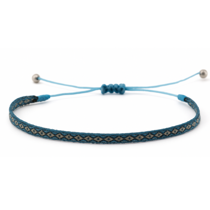 Woven bracelet with a blue and turquoise diamond pattern, worn on wrist alongside other bracelets.
