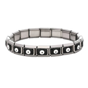 A stainless steel bracelet featuring black evil eye motifs arranged in rectangular links, laid in a circular form on a white background.