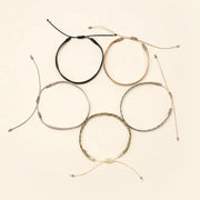 Set of five adjustable bracelets in various colors on a beige background
