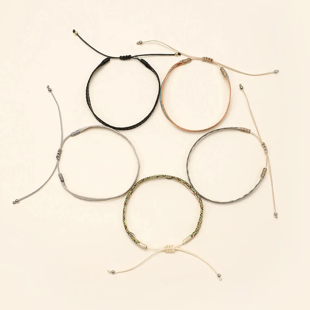 Set of five adjustable bracelets in various colors on a beige background