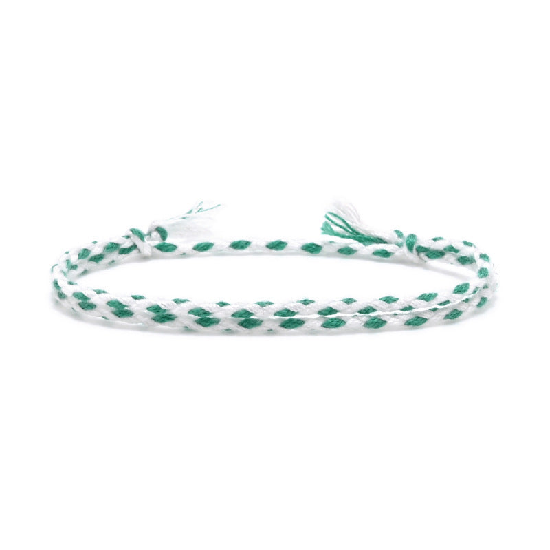 Handmade double braided friendship bracelet in emerald green and white cotton thread, styled on wrist