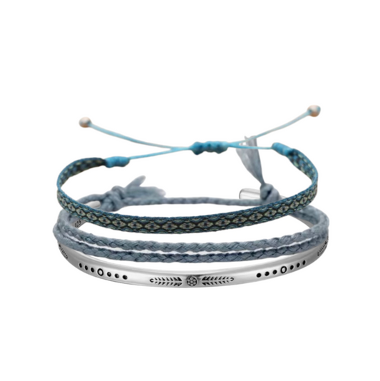 Three-piece bracelet set with a woven blue band, braided grey rope bracelet, and silver engraved cuff, worn on wrist.