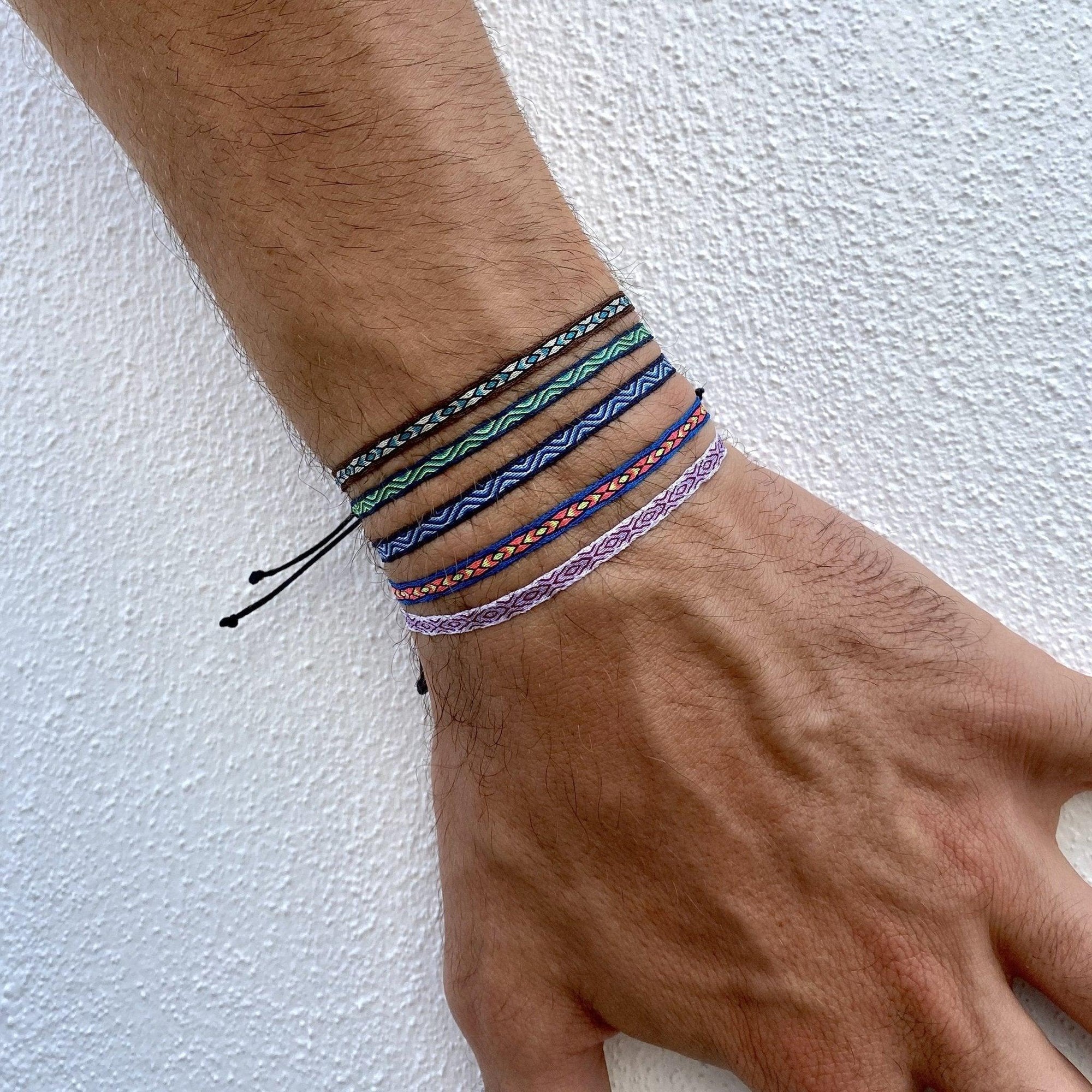 Hand wearing multiple colorful bracelets on a white background