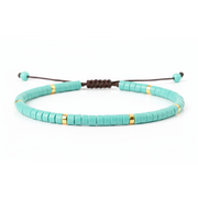 Turquoise beaded bracelet with gold accents on a white background